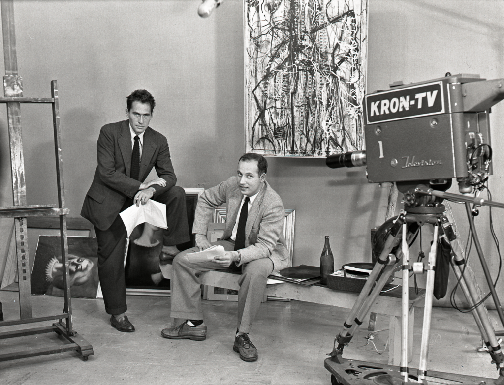 A black and white photograph of two Caucasian men sitting in an old TV studio