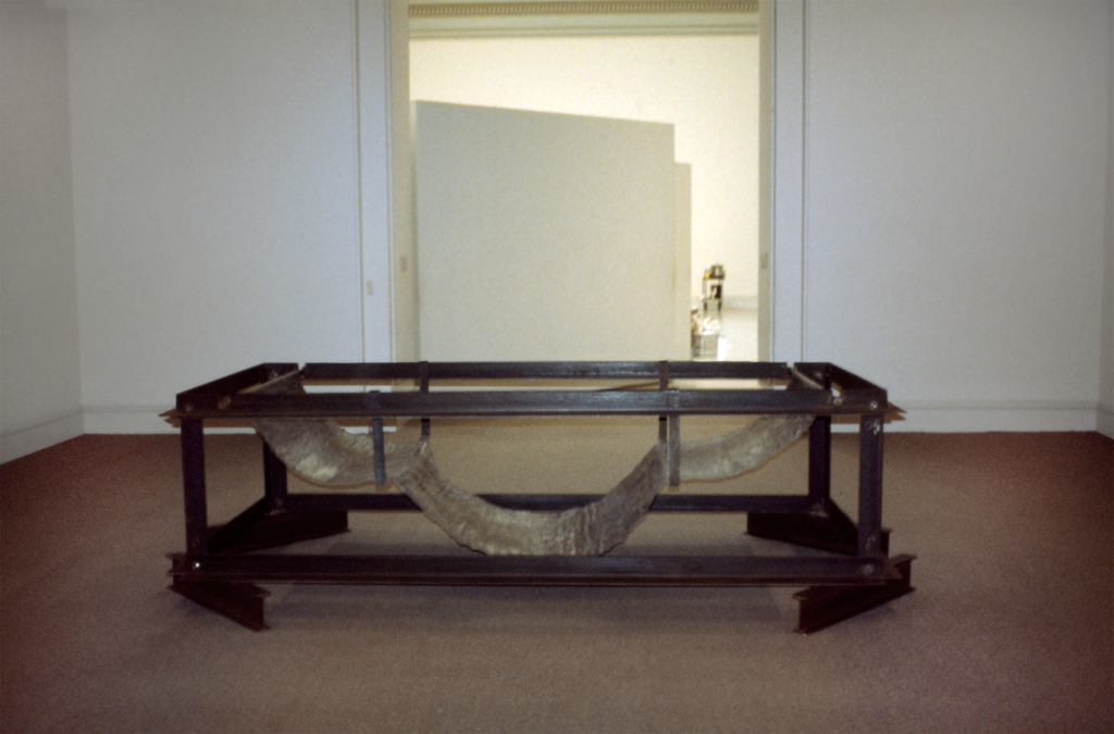 A large, rusted metallic sculpture in a gallery